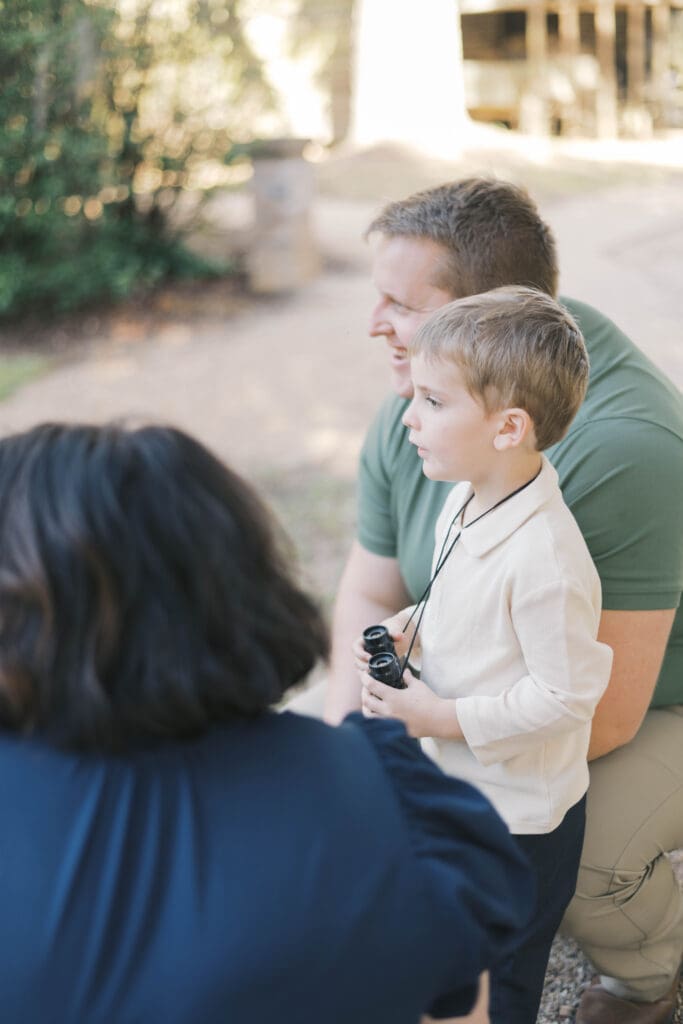a family looks in the distance while the boy holds his binoculars for a candid shot