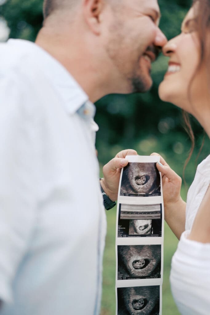 A mom and dad almost kiss with the baby sonogram as the focus between them