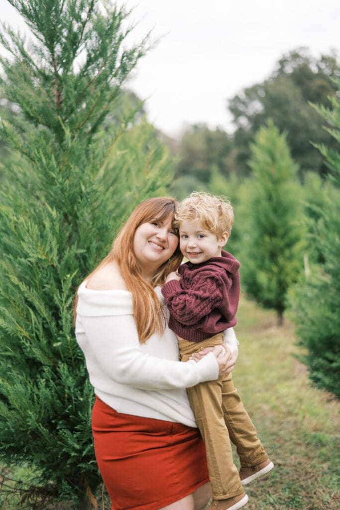 A aunt and her nephew smile at the camera amongst Christmas Tree near Baton Rouge